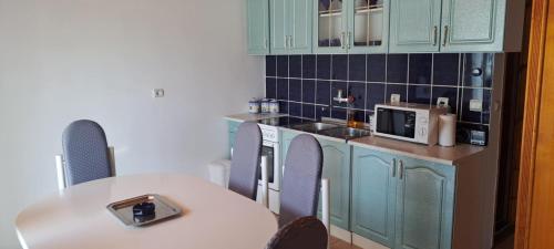 a kitchen with blue cabinets and a white table and chairs at Đenovici Apartmans in Ðenovići