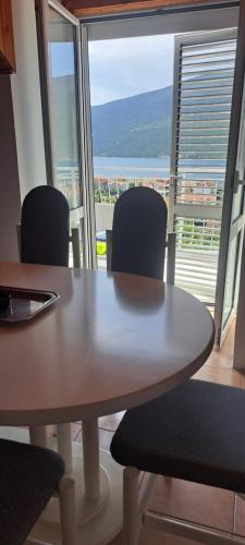 a table and chairs in a room with a large window at Đenovici Apartmans in Ðenovići