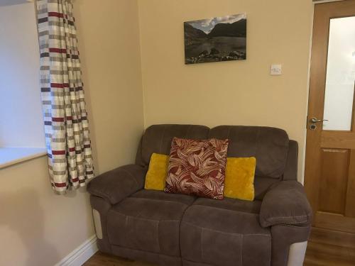 a brown couch with two pillows on it in a room at Colleen Bawn Cottage Gap Of Dunloe Kerry in Killarney