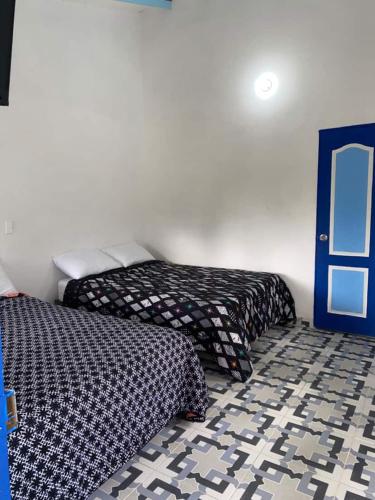 a bedroom with two beds and a blue door at Vista Farallones Hostel in Jardin