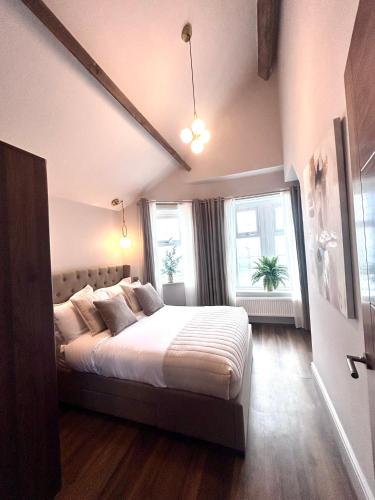 a bedroom with a bed and two windows at Luxury Penarth Loft - Near Cardiff in Penarth