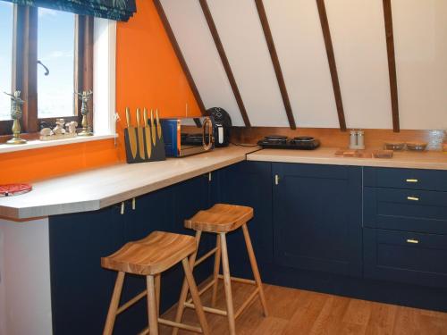 a kitchen with blue cabinets and two wooden stools at Kingfisher Granary in Ashburnham