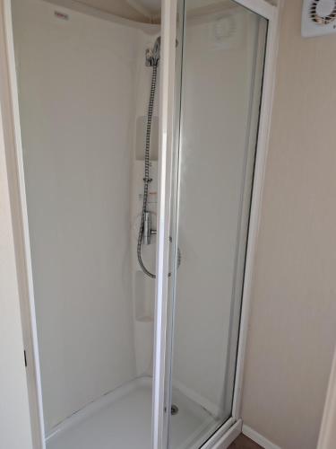 a shower with a glass door in a bathroom at 3 bed Sleeps 8 Wifi and Linen inc in Corton