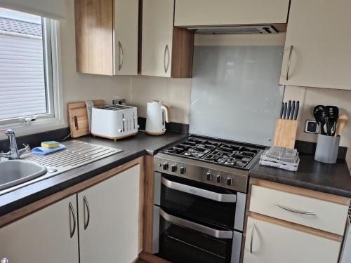 a kitchen with a stove top oven next to a sink at 3 bed Sleeps 8 Wifi and Linen inc in Corton