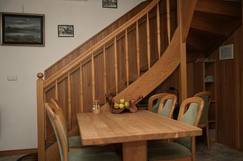a wooden table with chairs and a staircase at Miškar Rooms in Cerknica
