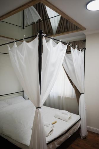 a canopy bed with white sheets and towels on it at Cozy Hideaway Your Urban Escape in Craiova