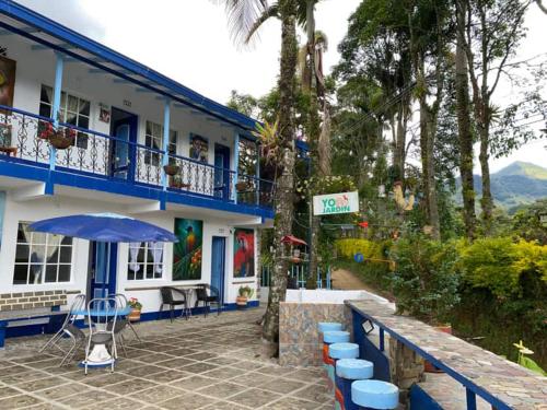 a building with blue chairs and an umbrella in front of it at Vista Farallones Hostel in Jardin