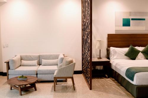 a bedroom with a bed and a couch and a mirror at Castillete Hotel & Beach Club in Tierra Bomba