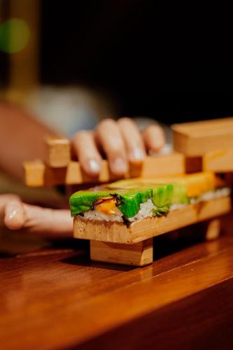 a person is holding a stack of tofu on a table at Casa Las Tortugas Petit Beach Hotel & Spa in Holbox Island
