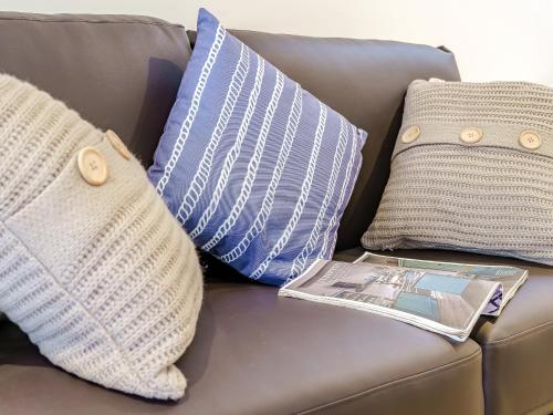 a couch with pillows and a magazine on it at Ty Draenog - Uk31653 in New Quay