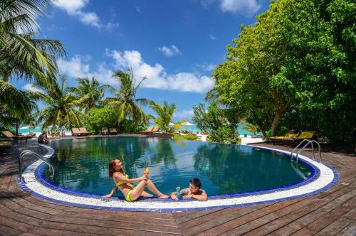 dos chicas sentadas en la piscina en un resort en Adaaran Prestige Vadoo - Adults Only Premium All Inclusive with Free Transfers, en Atolón de Malé Sur