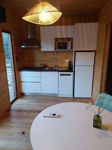 a kitchen with white cabinets and a white table at Fragas do Cabril Eco & Wellness Lodge in Lousã
