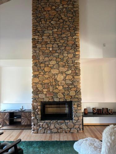 a stone fireplace in a living room with a stone wall at Fragas do Cabril Eco & Wellness Lodge in Lousã