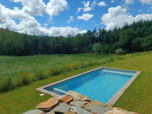 a swimming pool in the middle of a field at Fragas do Cabril Eco & Wellness Lodge in Lousã