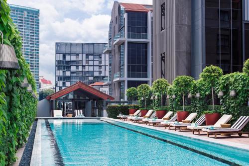 una piscina con tumbonas y edificios en M Social Singapore en Singapur
