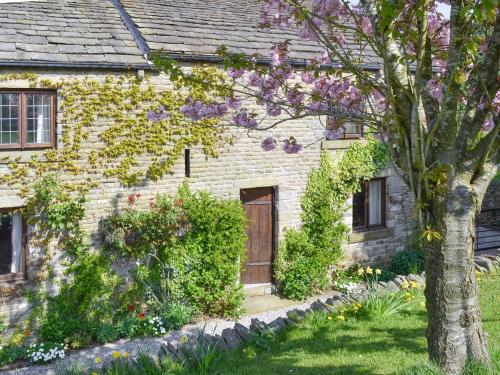 an old brick house with a door and flowers at Townfield Farm in Chinley