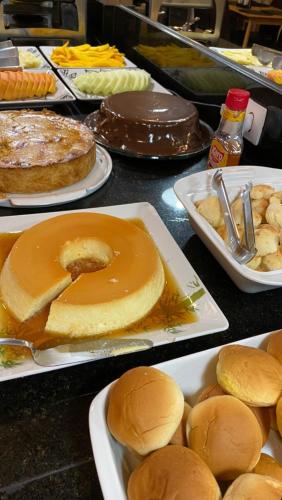 Una mesa cubierta con platos de comida con bollos y pasteles. en Suites Flamengo, en Río de Janeiro