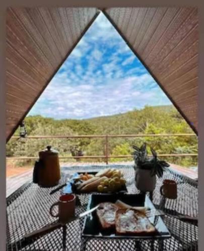 a table with food on a balcony with a window at Chalés do AVOHAY, lindo chalé com privativo ofurô aquecido,apenas 2 minutos da Vila de São Jorge in Sao Jorge
