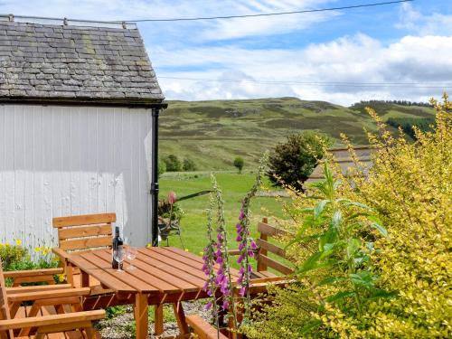 a wooden table and bench in a garden at Dalvanie Mill - S4241 in Tulchan