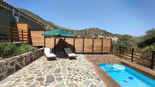 a patio with a pool and an umbrella and chairs at Litinos Villas in Fodele