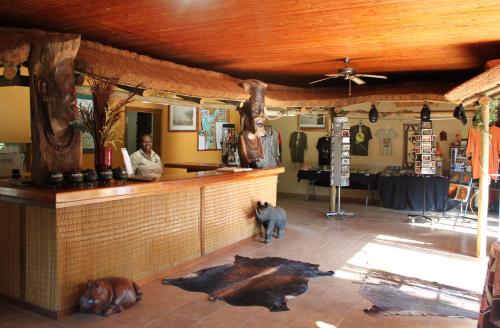 a man and a dog standing at a bar in a restaurant at Gooderson Bushlands Game Lodge in Hluhluwe