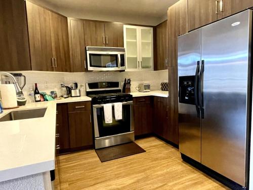 a kitchen with wooden cabinets and a stainless steel refrigerator at Designer 2 Bedroom with 3 Beds- Pool View, Gym, Parking in Los Angeles