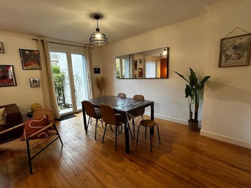 a dining room with a table and chairs and a mirror at La Dragonnière Maison AVEC jardin in Calais