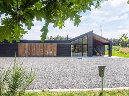 a house with a black roof and a gravel driveway at 5 star holiday home in Glesborg in Glesborg