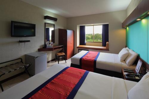 Habitación de hotel con 2 camas y TV de pantalla plana. en Microtel by Wyndham Eagle Ridge en General Trias