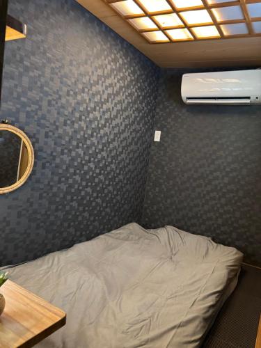 Bett in einem Zimmer mit grauer Wand in der Unterkunft Surfer's Cafe& Hostel in Chatan