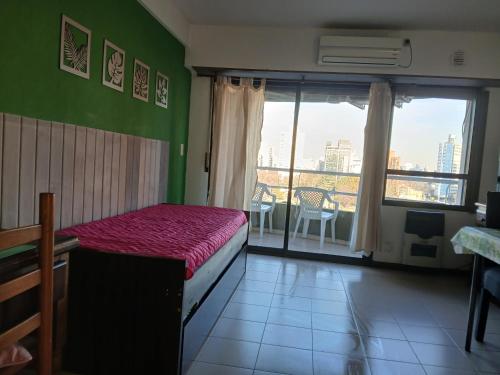 a bedroom with a bed and a balcony with a view at Departamento Plaza Moreno con balcón in La Plata
