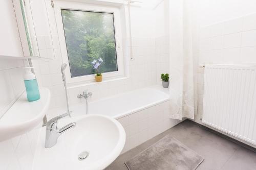 a white bathroom with a sink and a toilet and a window at TOP PREMIUM UNTERKUNFT in KÖLN - HÜRTH! in Hürth
