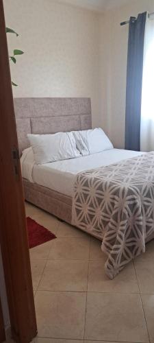 Una cama en un dormitorio con ventana. en Appartement hory, en Martil