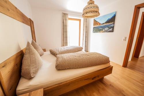 Bett in einem Zimmer mit einem großen Fenster in der Unterkunft Ferienhaus am Rohntalbach in Hinterriss