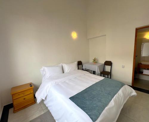 a bedroom with a large white bed and a table at Hotel Villa Macondo in Villa de Leyva