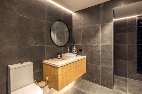 a bathroom with a toilet and a mirror at Moa Luxe - Stay Waiheke in Waiheke Island