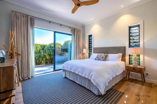 a bedroom with a bed and a large window at Moa Luxe - Stay Waiheke in Waiheke Island