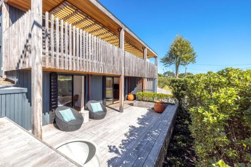 a house with a deck with chairs on it at Moa Luxe - Stay Waiheke in Waiheke Island