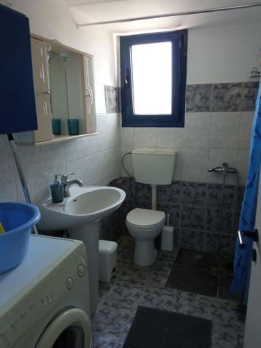a bathroom with a sink and a toilet and a window at Lychnaria Apartments Κάτω Νότιο in Moudhros