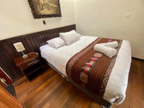 a bedroom with a bed and a table with a night stand at Inka's Stone Urubamba in Urubamba