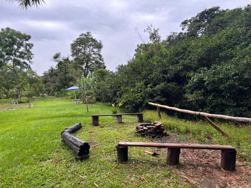 a park with two benches and a fire pit at Cabaña Jacaranda #1, Pérez Zeledón in Roble