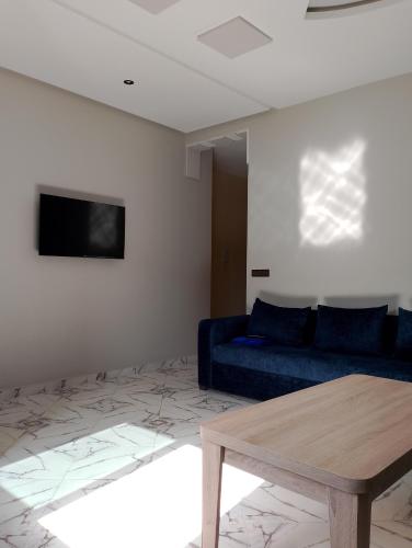 a living room with a blue couch and a table at Appartement Wad Marsa in Taoutiet el Bioute