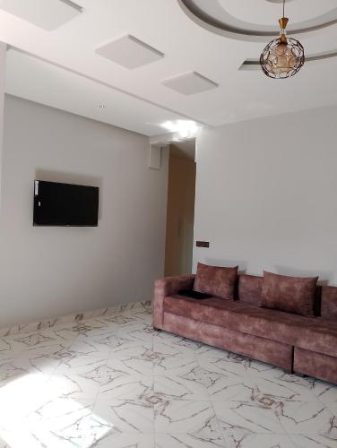 a living room with a couch and a flat screen tv at Appartement Wad Marsa in Taoutiet el Bioute