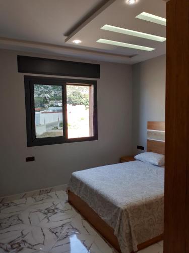 a bedroom with a bed and a window at Appartement Wad Marsa in Taoutiet el Bioute