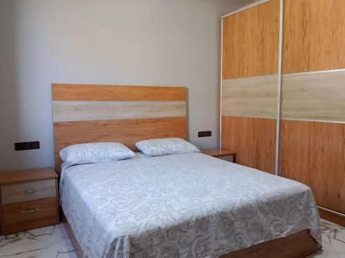 a bedroom with a bed and a wooden headboard at Appartement Wad Marsa in Taoutiet el Bioute