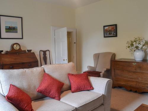 a living room with a couch with two red pillows at East Monkton Farm Cottage in Wick