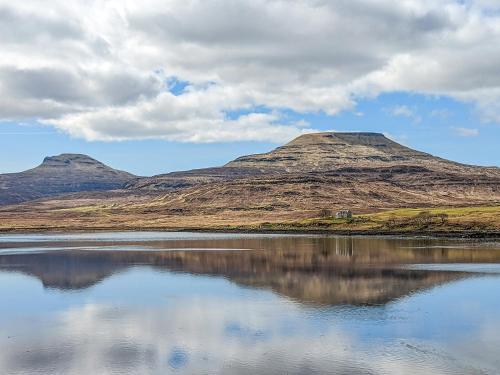 a reflection of two mountains in a body of water at The Beach House in Dunvegan