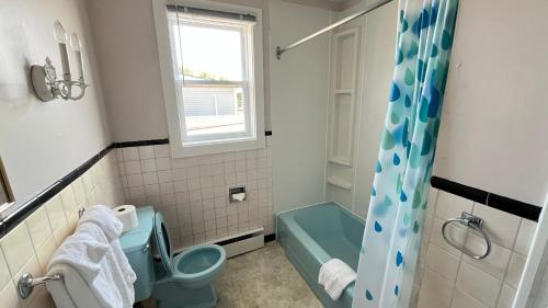 Un baño con inodoro azul y ducha. en Admiral's Quay Motel & Suites, en Saint John