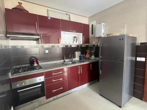 a kitchen with red cabinets and a stainless steel refrigerator at Turquoise Fnideq in Riffiene