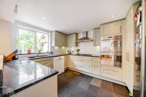 a kitchen with white cabinets and stainless steel appliances at EEJs Luxe 5 Bed Home - Greenwich in London